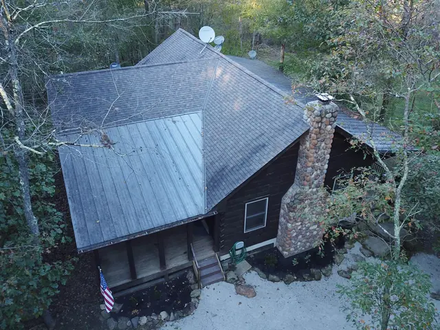 Low aerial view of the cabin roof, porch and stone chimney