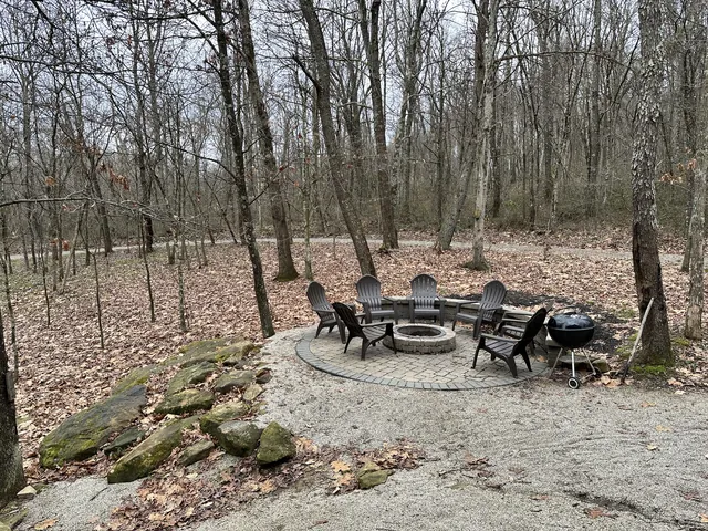 Stone fire pit and chairs in the woods in late fall