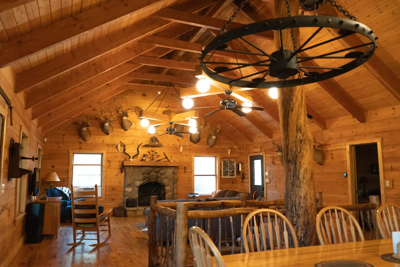 Great room at Serenity Lodge, one of the Hocking Hills cabins for groups, with a log ceiling and wagon wheel chandelier