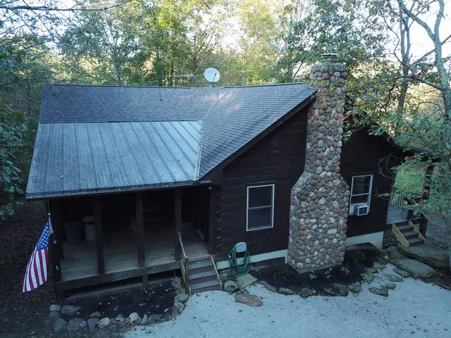 Front of the log cabin with its covered porch and stone chimney